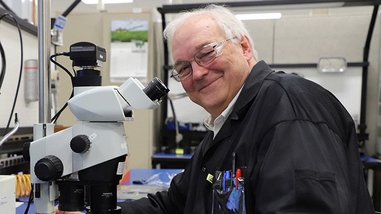 Dr. William F. Cooper stând lângă un microscop