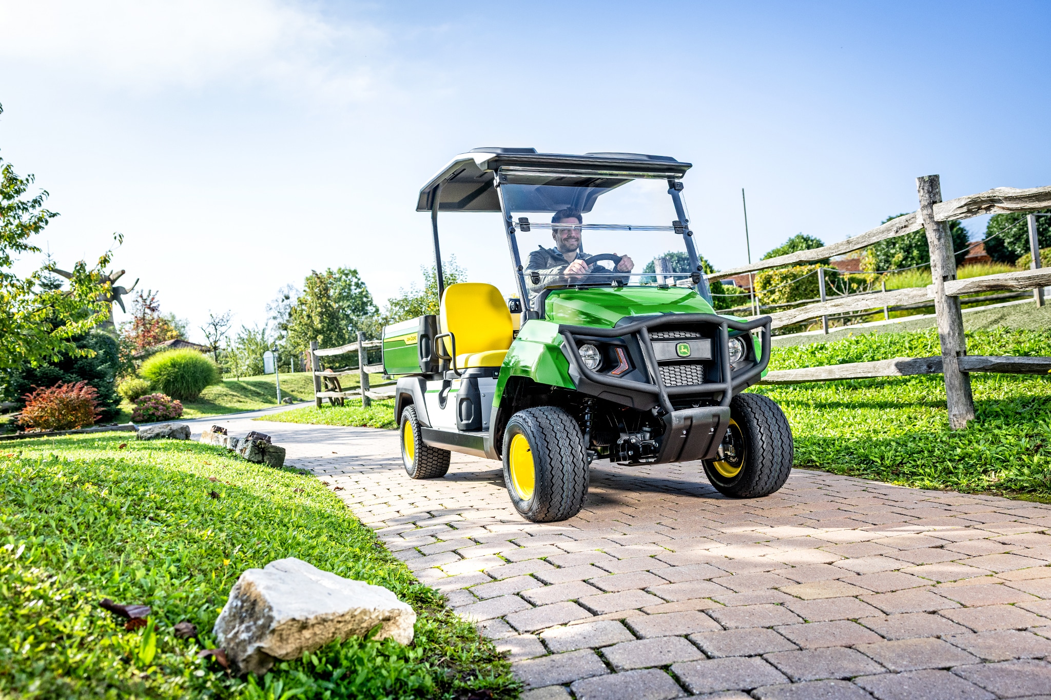 Vehicul utilitar Gator GS care circulă pe un drum pavat într-o zonă amenajată Vehicul utilitar Gator GS care circulă pe un drum pavat într-o zonă amenajată