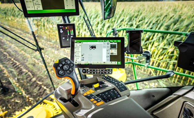 Combină de furaje autopropulsată F9 700 care încarcă o remorcă Joskin trasă de un tractor John Deere 6R