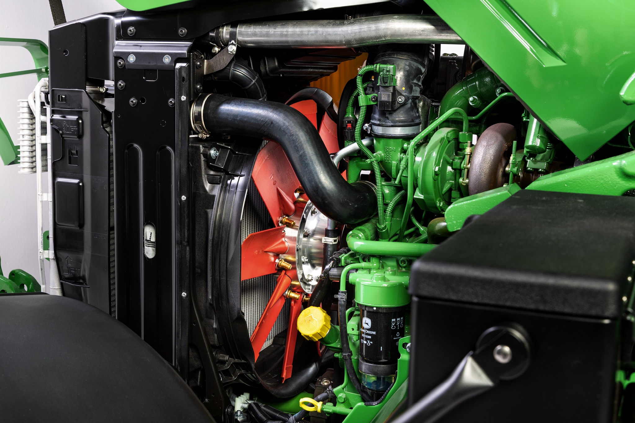 Vedere de aproape a compartimentului motor John Deere seria 6M, care evidenţiază sistemul de răcire şi componentele motorului.