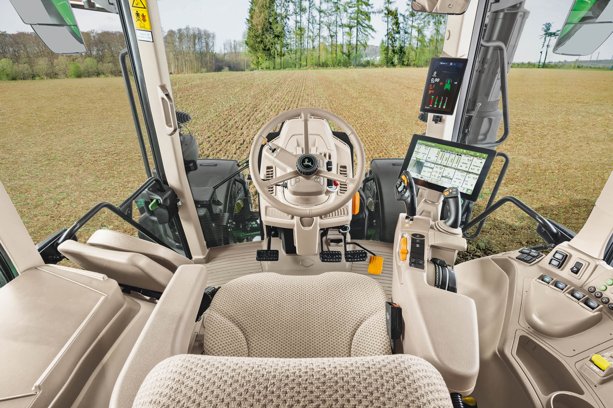 Prezentare generală a cabinei tractorului John Deere seria 6M cu scaun pentru operator, volan şi afişaje digitale.