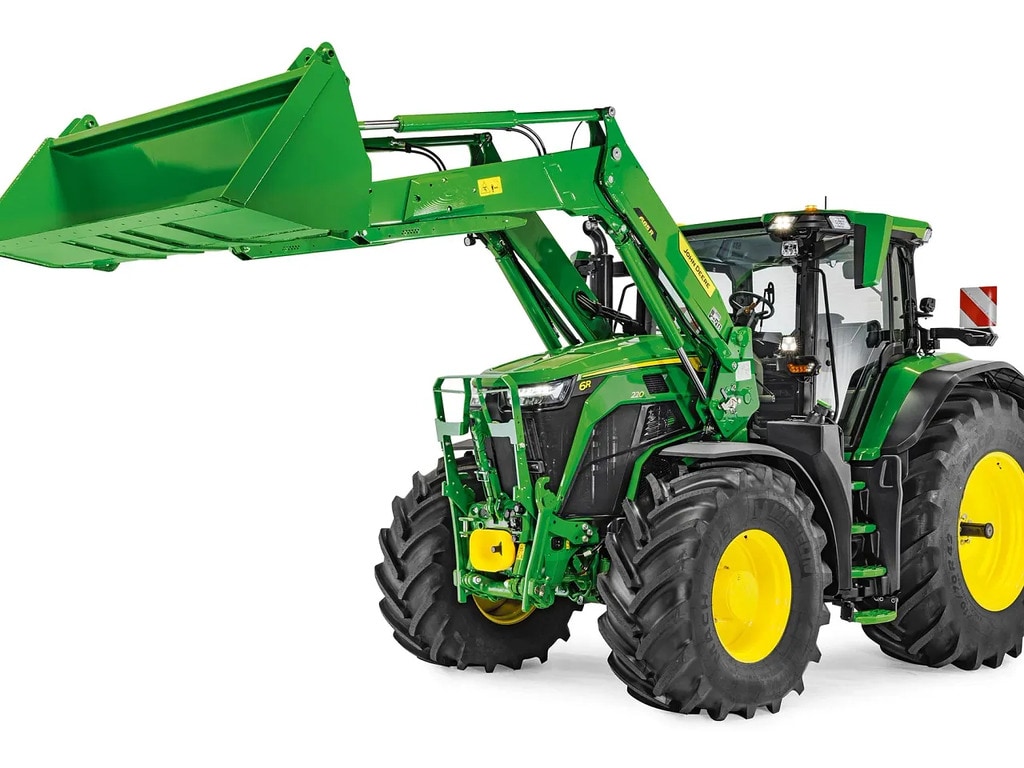 Tractor John Deere cu încărcătorul frontal coborât şi cupa ataşată, izolat pe fundal alb.